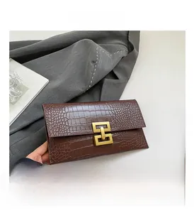Detail of dark brown stone textured envelope clutch featuring a matte gold geometric clasp