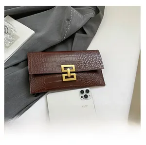 Detail of dark brown stone textured envelope clutch with gold buckle and phone for size