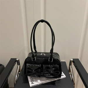Retro black leather shoulder bag with bow pockets on a minimalist metal chair