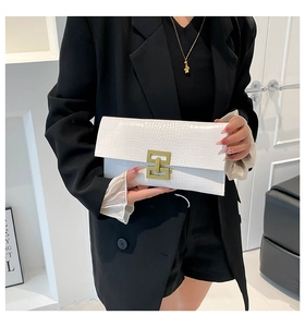 Detail of white crocodile texture envelope clutch with gold geometric metal clasp closure