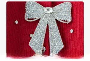 Close-up of red knit sweater featuring a sparkling rhinestone bow with a center gem