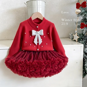 Detail of red knitted cardigan with white bows and pearls paired with a tutu skirt