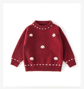 Detailed close-up of dark red knitted sweater with white mushroom appliques and embroidery