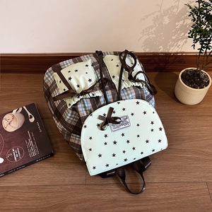 Mint green school backpack with plaid pattern and bow tie in a cozy home setting