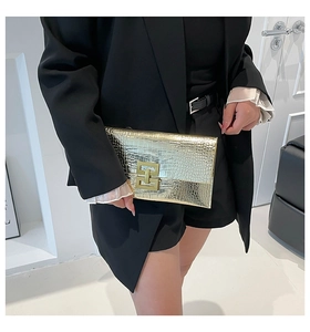 Close-up of golden crocodile texture envelope clutch with geometric metallic buckle