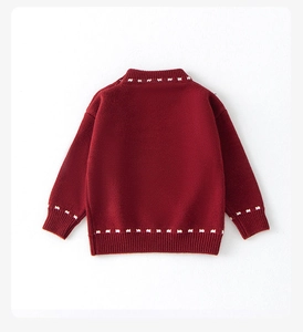 Detail view of red knitted girls' sweater featuring white stitching and premium texture