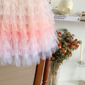 Detail of pink gradient tiered tulle cake dress for girls hanging on a wooden chair