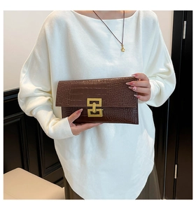 Detail of dark brown faux crocodile leather envelope clutch with a gold geometric clasp