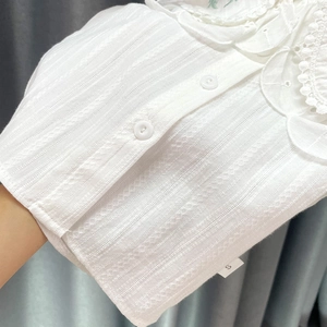 Détail d'une chemise en coton blanc avec bordure en dentelle et broderie ajourée