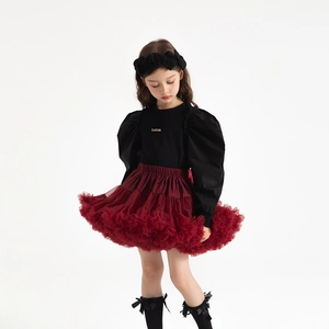 Detail of girls' burgundy layered tulle tutu skirt paired with a black puff sleeve top