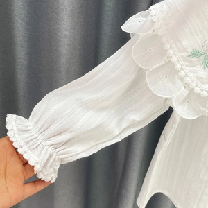Détail d'une chemise blanche pour fille avec col brodé et poignets élastiques en dentelle