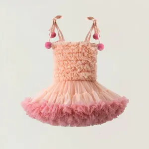 Detail of pink tutu dress featuring multi-layer mesh skirt and pom-pom shoulder straps