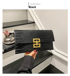 Detail of black stone-pattern clutch bag featuring a gold geometric twist lock closure