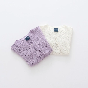 Detail of baby knit cardigans showing intricate openwork patterns and buttons