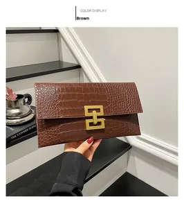 Detail of brown crocodile pattern envelope clutch featuring a square gold metal lock buckle