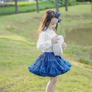 Outdoor shot of a girl wearing a fluffy navy blue layered tutu skirt with a white blouse