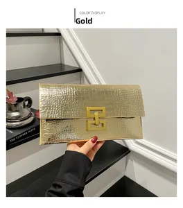Detail of gold envelope clutch bag with crocodile texture and interlocking metal lock