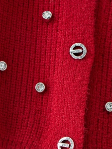 Detail of red knit sweater for girls featuring sparkling rhinestone metal buttons