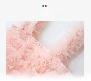 Detailed close-up of layered pink tulle mesh showing dense floral bud ruffles on a tutu dress