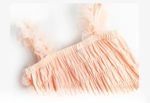 Detail of pink cotton tutu dress showing elastic smocked bodice and ruffled straps