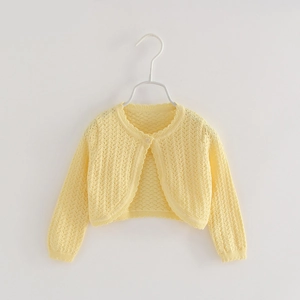 Detail of light yellow knit bolero for girls featuring hollow patterns and a pearl button