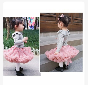 Detail of pink layered tutu skirt with grey ruffle top worn by girl in garden