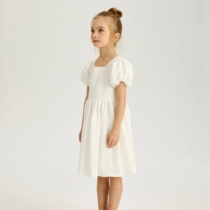 Détail de robe blanche pour fille avec col carré et manches bouffantes en coton
