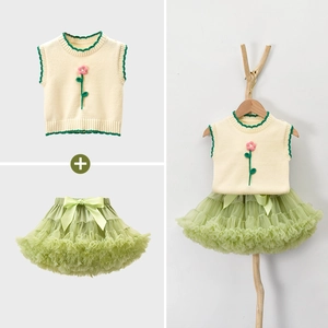 Dettaglio di gilet in maglia per bambine con fiori rosa e gonna tutu in tulle verde a strati