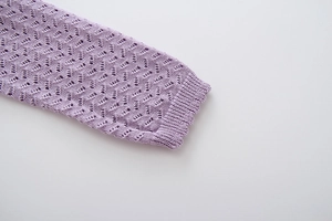 Detail of light purple knit cardigan featuring hollow wave patterns and scalloped lace edges