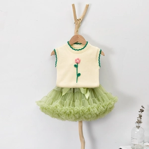 Dettaglio del gilet in maglia con ricami e gonna tutu in rete verde a strati