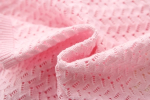 Detailed macro view of pink hollow-out knit fabric with soft breathable wave texture