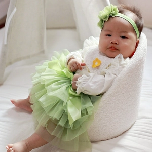 Detail view of baby girl tutu set with lace top and floral headband on soft pillow