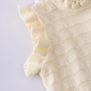 Détail du motif en tricot ajouré et des manches à volants sur ce haut de couleur crème