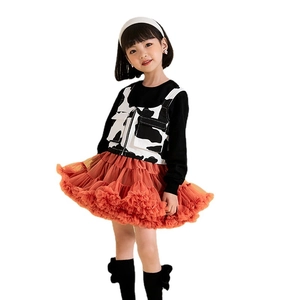 Girls' outfit with black long-sleeve top, cow print vest, and orange layered tutu skirt