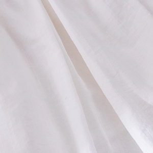 Texture macro détaillée du tissu en coton et lin blanc montrant le tissage naturel de la robe