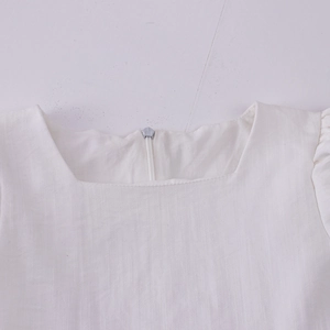 Détail d'une robe blanche pour filles à col carré avec texture coton et zip au dos