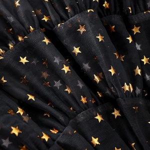 Detailed macro view of black tulle fabric with sparkling gold and silver sequin stars