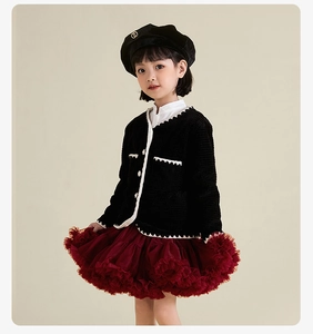 Detail of girls' black knit cardigan with scallop embroidery and red tutu skirt