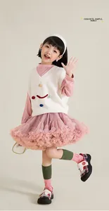 Detailed view of pink layered tutu skirt and white knitted vest with colorful 3D accents