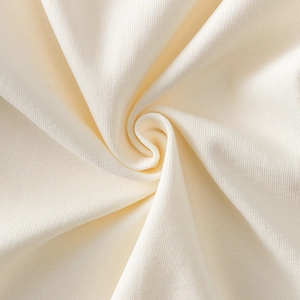 Detailed macro view of ivory hollow knit fabric with soft texture and ruffled lace edges