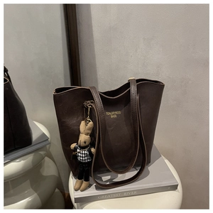 Detail of dark brown faux leather tote with golden lettering and a rabbit pendant