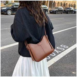 Detail view of brown leather crossbody bag with stitching and adjustable shoulder strap