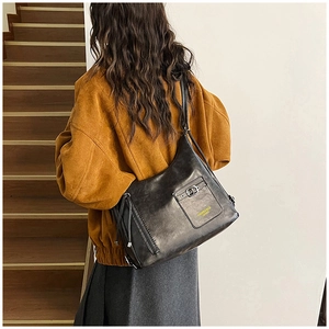 Vue arrière du modèle portant un grand sac cabas en cuir noir avec boucle métallique chic