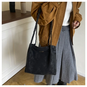 Detail of black faux suede tote bag featuring distinctive double-braided shoulder straps