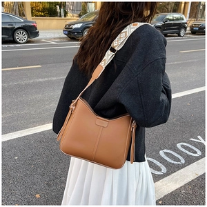 Detail of tan leather crossbody bag with vintage geometric pattern wide shoulder strap