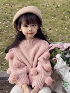 Detailed texture of pink knit girls sweater featuring fluffy 3D decorative pompoms