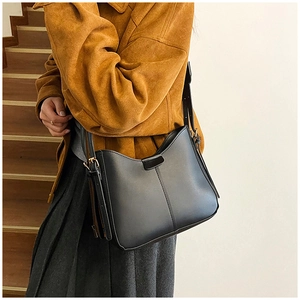 Detail of minimalist black leather crossbody bag with adjustable strap and golden buckle