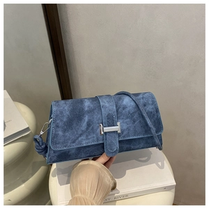 Detalle del bolso baguette denim azul con hebilla plateada y asa anudada en el soporte