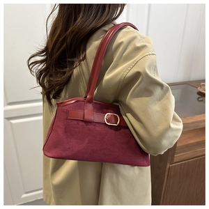 Close-up of burgundy suede shoulder bag with a gold metal buckle on a trench coat