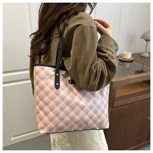 Detail of pink and white checkered tote bag with black strap and golden rivets